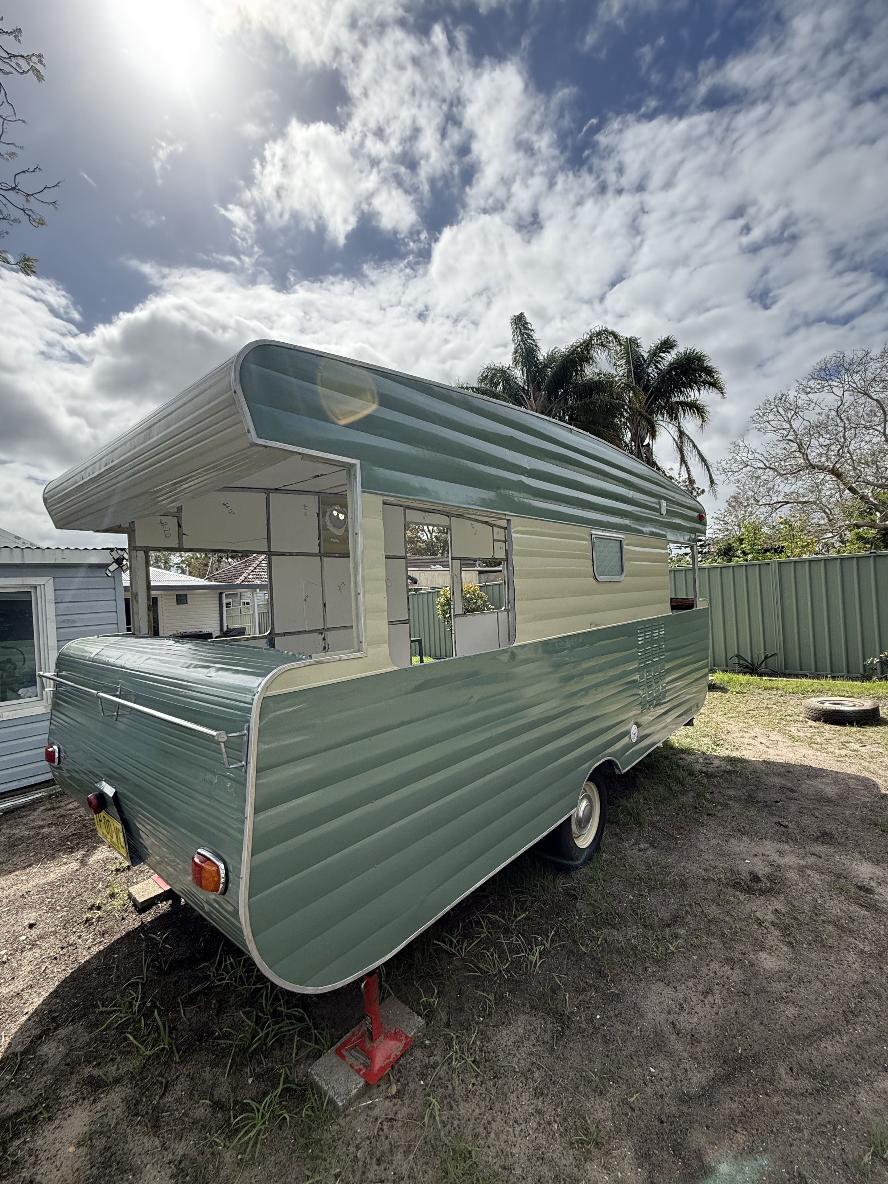 Rear and side of the caravan with open window frames during the restoration.